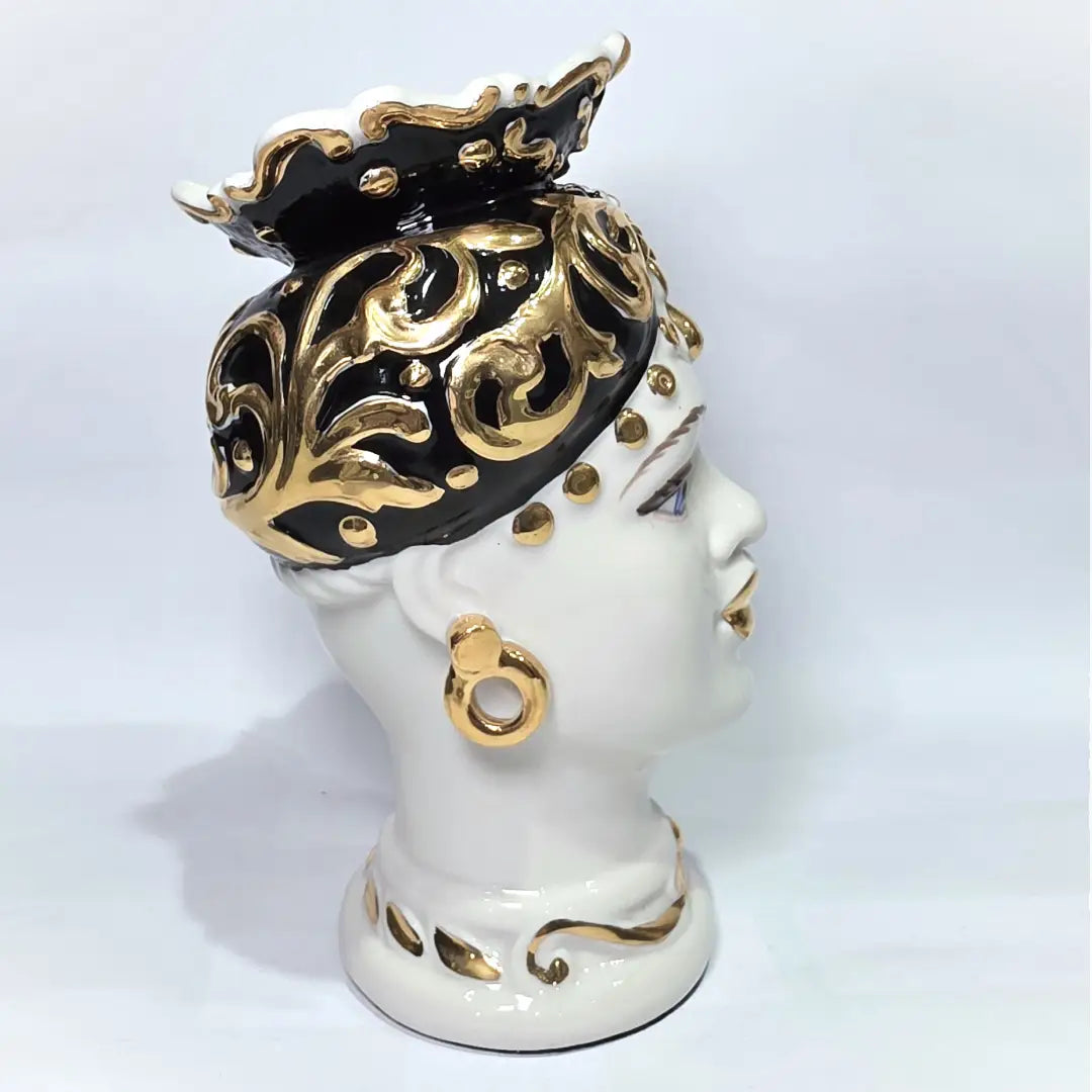Coppia di Teste di Moro in ceramica artigianale bianca lucida con turbanti neri riccamente decorati da fregi e dettagli in oro zecchino. Queste sculture ornamentali raffiguranti un uomo con baffi e una donna con labbra dorate sono complementi d'arredo di lusso che reinterpretano la tradizione siciliana in chiave moderna ed elegante.