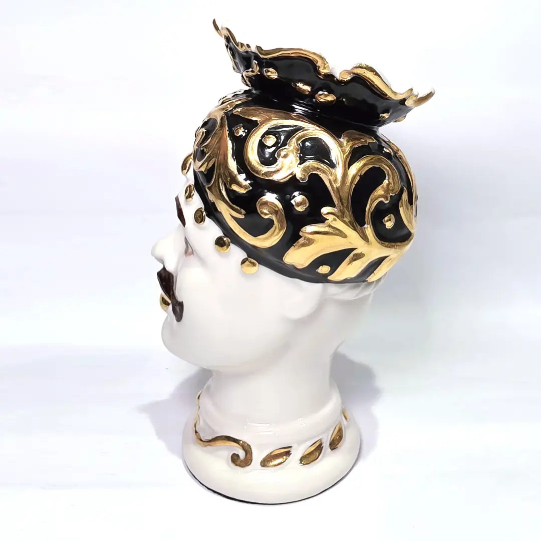 Coppia di Teste di Moro in ceramica artigianale bianca lucida con turbanti neri riccamente decorati da fregi e dettagli in oro zecchino. Queste sculture ornamentali raffiguranti un uomo con baffi e una donna con labbra dorate sono complementi d'arredo di lusso che reinterpretano la tradizione siciliana in chiave moderna ed elegante.
