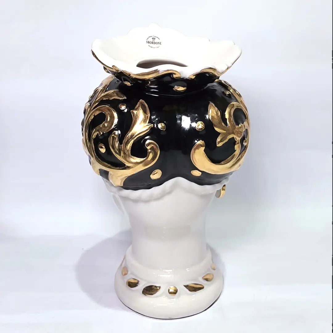 Coppia di Teste di Moro in ceramica artigianale bianca lucida con turbanti neri riccamente decorati da fregi e dettagli in oro zecchino. Queste sculture ornamentali raffiguranti un uomo con baffi e una donna con labbra dorate sono complementi d'arredo di lusso che reinterpretano la tradizione siciliana in chiave moderna ed elegante.