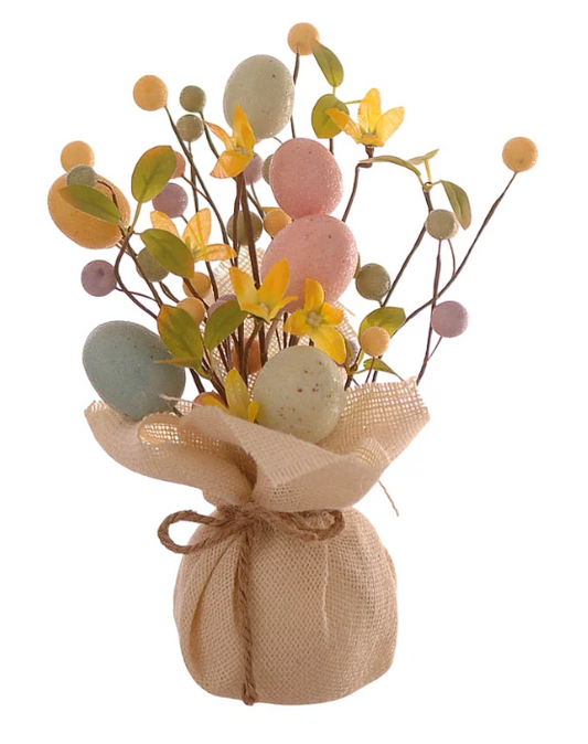Statuina decorativa pasquale a forma di piccolo alberello o bouquet. La base è costituita da un sacchetto in tela di juta color crema, chiuso da un cordino in spago naturale. Dal sacchetto si sprigionano rami sottili decorati con uova di Pasqua in tonalità pastello (rosa, azzurro e giallo), piccoli fiori gialli e bacche coordinate. Design rustico e primaverile.