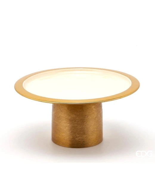 Alzata Charm rotonda smaltata color avorio firmata EDG Enzo de Gasperi, caratterizzata da un piatto circolare con un elegante bordo dorato e supportata da una robusta base cilindrica in metallo color oro satinato. Questo raffinato vassoio con piedistallo di design si presta perfettamente come alzata per dolci, centrotavola decorativo o esclusivo espositore per impreziosire ambienti eleganti e cerimonie.
