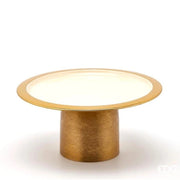 Alzata Charm rotonda smaltata color avorio firmata EDG Enzo de Gasperi, caratterizzata da un piatto circolare con un elegante bordo dorato e supportata da una robusta base cilindrica in metallo color oro satinato. Questo raffinato vassoio con piedistallo di design si presta perfettamente come alzata per dolci, centrotavola decorativo o esclusivo espositore per impreziosire ambienti eleganti e cerimonie.