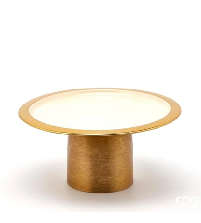 Alzata Charm rotonda smaltata color avorio firmata EDG Enzo de Gasperi, caratterizzata da un piatto circolare con un elegante bordo dorato e supportata da una robusta base cilindrica in metallo color oro satinato. Questo raffinato vassoio con piedistallo di design si presta perfettamente come alzata per dolci, centrotavola decorativo o esclusivo espositore per impreziosire ambienti eleganti e cerimonie.