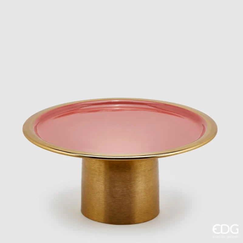Alzata Charm rotonda smaltata color salmone firmata EDG Enzo de Gasperi, caratterizzata da un piatto circolare con un elegante bordo dorato e supportata da una robusta base cilindrica in metallo color oro satinato. Questo raffinato vassoio con piedistallo di design si presta perfettamente come alzata per dolci, centrotavola decorativo o esclusivo espositore per impreziosire ambienti eleganti e cerimonie.