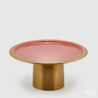 Alzata Charm rotonda smaltata color salmone firmata EDG Enzo de Gasperi, caratterizzata da un piatto circolare con un elegante bordo dorato e supportata da una robusta base cilindrica in metallo color oro satinato. Questo raffinato vassoio con piedistallo di design si presta perfettamente come alzata per dolci, centrotavola decorativo o esclusivo espositore per impreziosire ambienti eleganti e cerimonie.