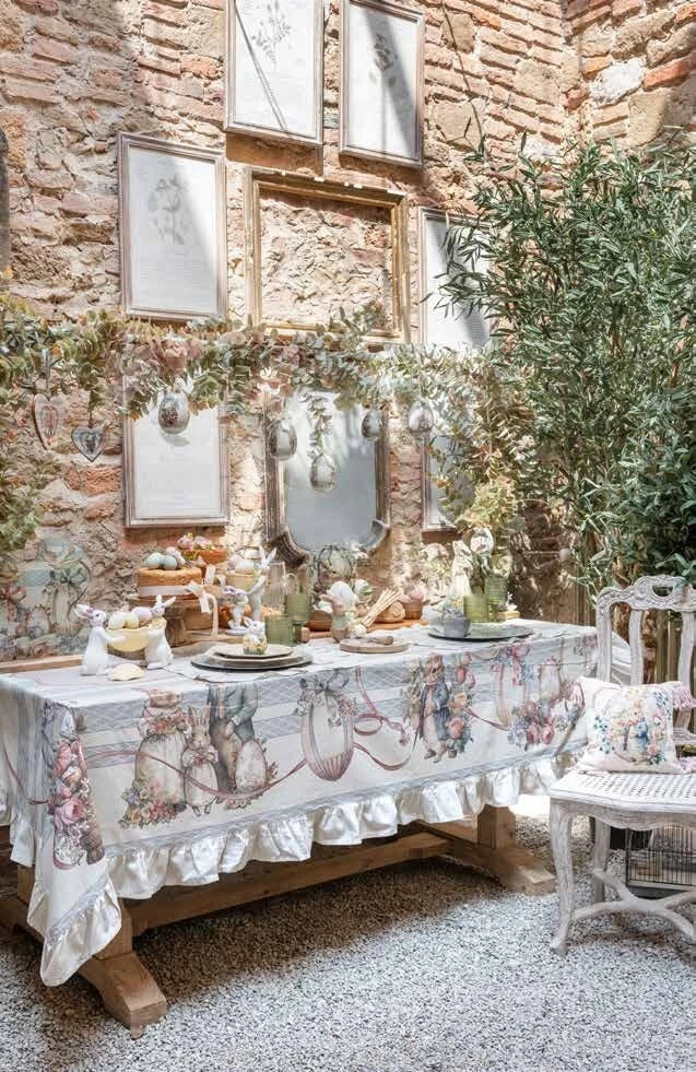 Runner da tavola della linea "Joyeuses Paques" caratterizzato da un'elegante trama a righe verticali beige e azzurre con decorazioni d'ispirazione vintage. Il pannello centrale nei toni del rosa racchiude una raffinata illustrazione pasquale con un coniglietto dentro un cesto intrecciato, uova colorate e rose, ideale per apparecchiare la tavola delle feste in perfetto stile shabby chic.