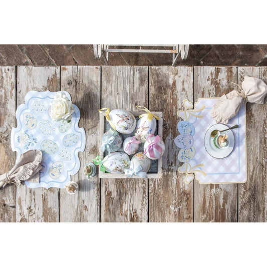 Tovaglietta americana in vinile della collezione "Pretty Easter" firmata Blanc Mariclo' con un motivo a scacchi bianchi e rosa perfetto per la colazione o il pranzo pasquale. La tovaglietta sagomata è decorata sul bordo superiore con fiocchi gialli e tre uova di Pasqua colorate nei toni pastello con dettagli floreali azzurri.