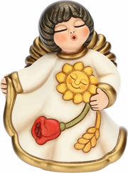 Statuina in ceramica Thun dell'Angelo della Mamma, Limited Edition "Giardino della Vita". L'angelo ha gli occhi chiusi, ali dorate e capelli castani sfumati; indossa una veste color crema con bordi dorati e tiene tra le mani un grande girasole sorridente, un tulipano rosso e una spiga di grano. Design iconico Thun con forme morbide e dettagli decorati a mano.