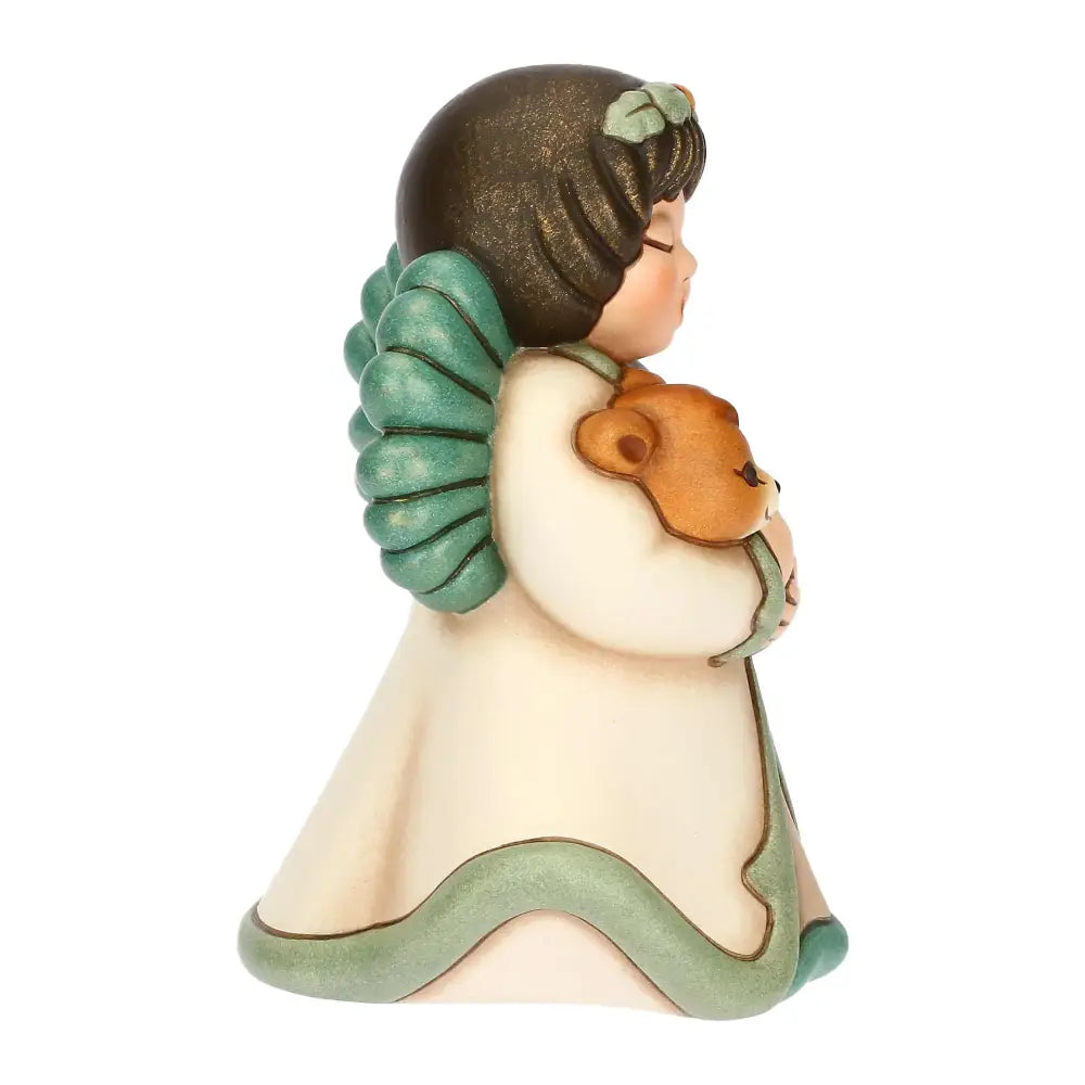 Statuina in ceramica Thun dell'Angelo della Natura Silvia, Limited Edition 2025, formato piccolo. L'angelo è raffigurato con gli occhi chiusi, ali verdi e una corona di foglie; indossa una veste color crema con bordi verdi e tiene tra le braccia, stringendolo al petto, un piccolo cerbiatto marrone. Design iconico Thun con finitura opaca e colori sfumati.