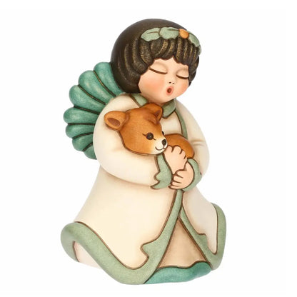 Statuina in ceramica Thun dell'Angelo della Natura Silvia, Limited Edition 2025, formato piccolo. L'angelo è raffigurato con gli occhi chiusi, ali verdi e una corona di foglie; indossa una veste color crema con bordi verdi e tiene tra le braccia, stringendolo al petto, un piccolo cerbiatto marrone. Design iconico Thun con finitura opaca e colori sfumati.