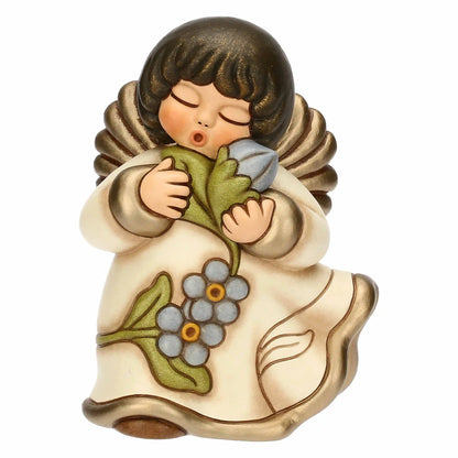 Statuina in ceramica Thun dell'Angelo dei Nonni Anna, collezione 2025. L'angelo è raffigurato con gli occhi chiusi, ali dorate e capelli castani. Indossa una veste color crema con bordi dorati e decorazioni floreali azzurre sulla parte inferiore. L'angelo tiene tra le mani un mazzo di fiori azzurri con foglie verdi, portandoli vicino al viso. Design classico Thun con finitura lucida e forme arrotondate.