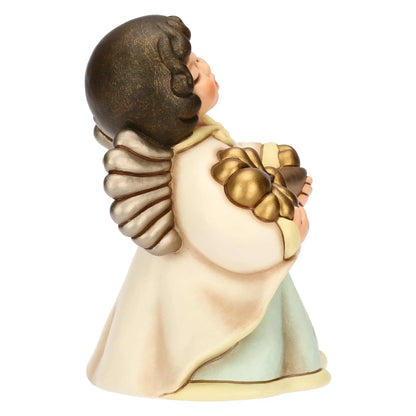 Inquadratura laterale di una statuina in ceramica raffigurante un angelo rivolto verso destra. La figura è scolpita in una posa inclinata in avanti, con il volto rivolto verso l'alto e la bocca socchiusa. L'angelo tiene tra le mani una grande chiave dorata, di cui si vede il profilo dell'impugnatura a forma di fiocco lobato e parte dell'asta. Indossa una veste color crema dai bordi giallo pastello che scivola su una tunica verde acqua.