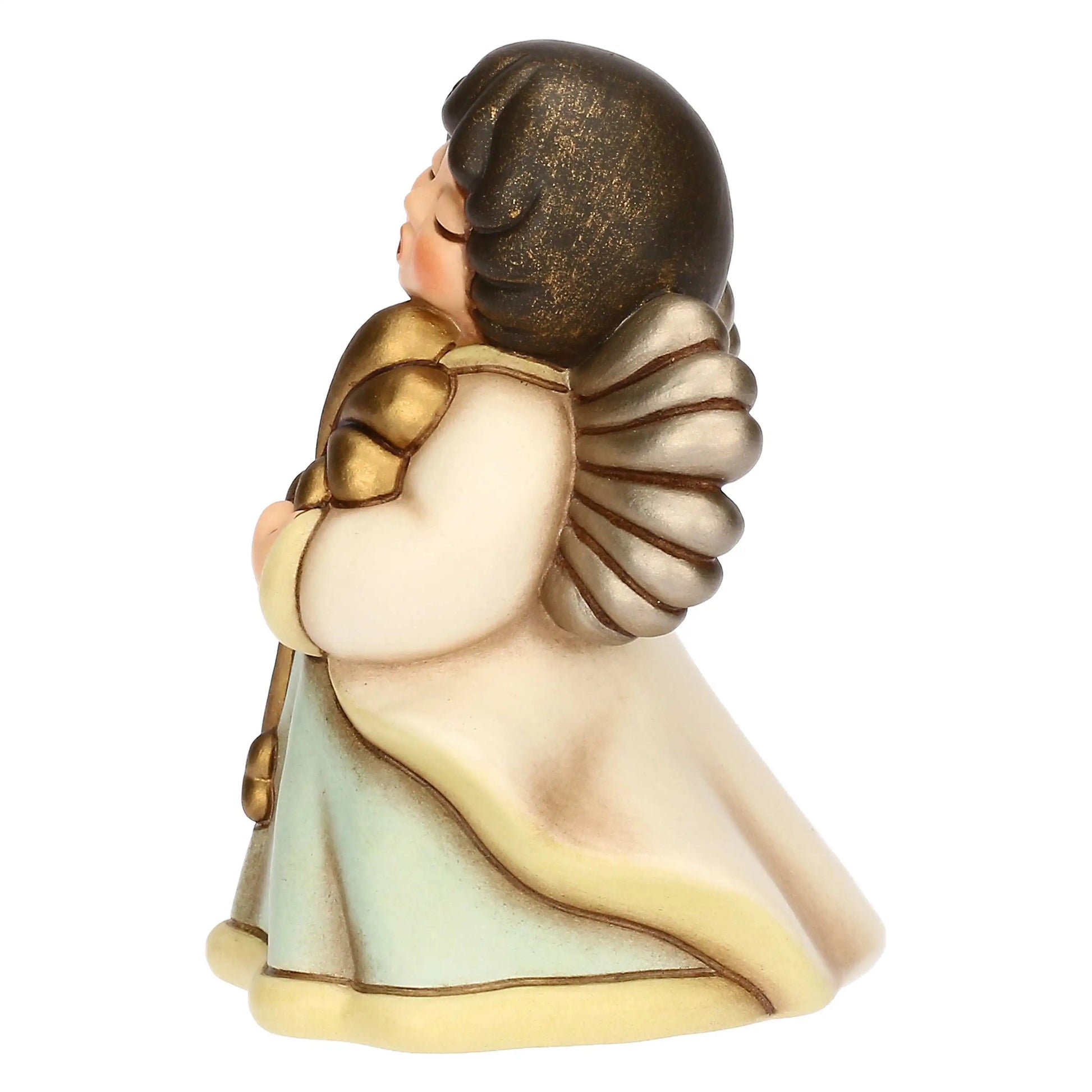 Inquadratura laterale sinistra della medesima statuina in ceramica, che mette in risalto il profilo dell'angelo e il volume degli abiti. In questa prospettiva è chiaramente visibile l'ala dorata con la sua texture a ventaglio e la curvatura del mantello bianco che scende morbido verso la base. Il volto dell'angelo è rivolto verso l'alto, mostrando le guance arrossate e il dettaglio dei capelli scuri. La base è bordata da una fascia gialla sfumata che segue la linea ondulata della veste verde acqua.