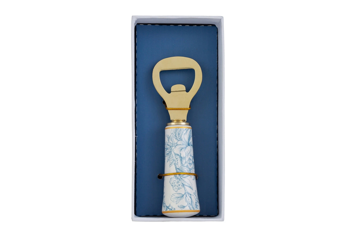 Apribottiglie con decoro azzurro firmato Le Stelle, caratterizzato da una solida testa in metallo color oro e un elegante manico in porcellana bianca decorato con delicati motivi floreali azzurri. Questo raffinato utensile da cucina e bar di design è accompagnato dalla sua custodia regalo rettangolare coordinata con la stessa fantasia botanica, perfetto come bomboniera di classe o idea regalo home decor.