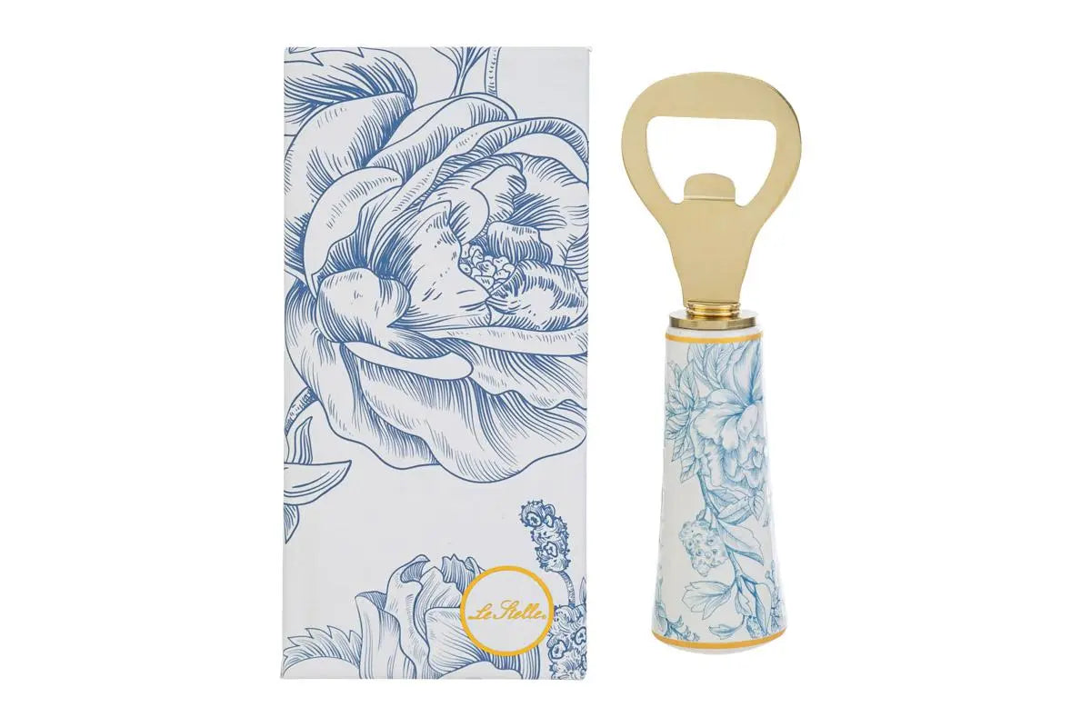 Apribottiglie con decoro azzurro firmato Le Stelle, caratterizzato da una solida testa in metallo color oro e un elegante manico in porcellana bianca decorato con delicati motivi floreali azzurri. Questo raffinato utensile da cucina e bar di design è accompagnato dalla sua custodia regalo rettangolare coordinata con la stessa fantasia botanica, perfetto come bomboniera di classe o idea regalo home decor.