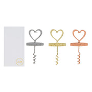 Cavatappi in metallo a forma di cuore con scritta "Love" incisa, disponibile in tre finiture assortite argento, oro e rosé, presentato accanto alla sua confezione bianca con logo "Le Stelle". Accessorio da tavola originale ideale come bomboniera o idea regalo per matrimoni ed eventi.