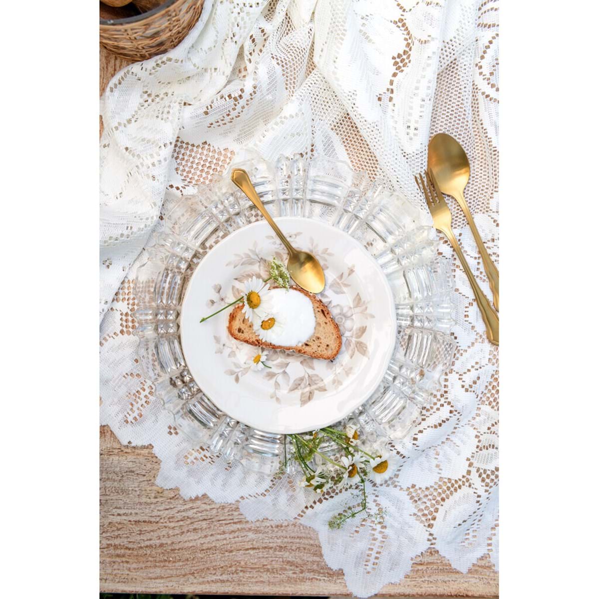 Tovaglia in pizzo bianco della collezione "Dentelle" di Blanc Mariclo' adatta per impreziosire la tavola con uno stile shabby chic ed elegante. Il dettaglio mostra due varianti assortite di tovaglie ricamate con motivi floreali e bordi smerlati ideali per la cucina o il soggiorno.