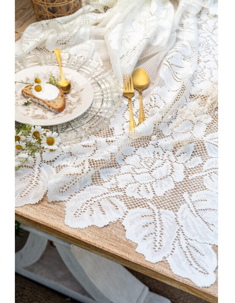 Tovaglia in pizzo bianco della collezione "Dentelle" di Blanc Mariclo' adatta per impreziosire la tavola con uno stile shabby chic ed elegante. Il dettaglio mostra due varianti assortite di tovaglie ricamate con motivi floreali e bordi smerlati ideali per la cucina o il soggiorno.