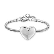 Bracciale in acciaio 316L lucido con maglia a serpente e grande pendente centrale a forma di cuore bombato. La chiusura a moschettone è rifinita con una serie di anellini e un piccolo charm a cuore.