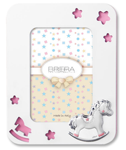 Portafoto per bambina in legno bianco con cornice sagomata e angoli arrotondati. Presenta trafori a forma di stelle e di un cavallino a dondolo che rivelano uno sfondo rosa pastello. In basso a destra è applicato un cavallino a dondolo in argento bilaminato con dettagli rosa sulle zampe e sulla sella. L'interno mostra un inserto decorativo con stelle e il logo "Brera - Real Italian Style".