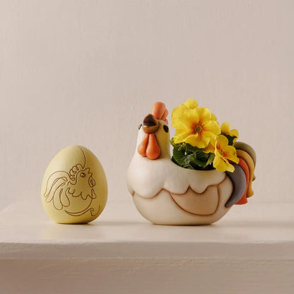 Cachepot in ceramica Thun a forma di gallo della collezione Incanto di Pasqua. Il contenitore presenta il corpo color crema, cresta e bargigli arancioni e una coda variopinta nei toni del verde, giallo, arancio e grigio azzurro. Design cavo sul dorso ideale come porta-piantina o svuotatasche pasquale.