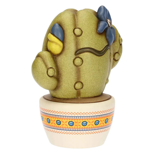 Scultura decorativa Cactus Frida di Thun in formato piccolo, realizzata in ceramica artigianale e impreziosita da fiori blu e gialli con l'iconico sopracciglio ispirato all'artista messicana. Questa statuina da collezione poggia su un vasetto bianco decorato con delicate trame etniche arancioni e blu, rappresentando un complemento d'arredo perfetto per regalare un tocco di colore e personalità agli spazi di casa.