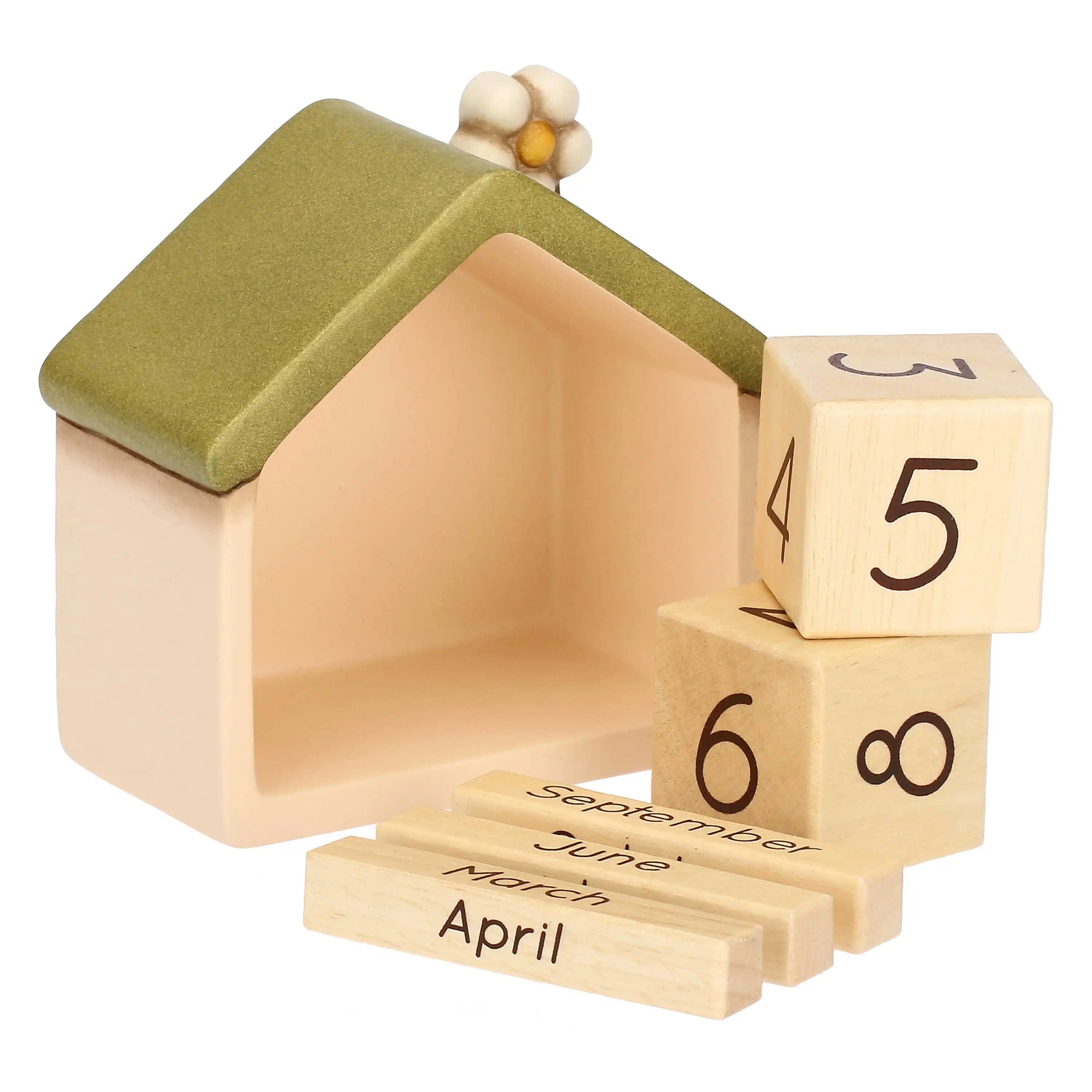 Questa immagine mostra il calendario con tutti i suoi componenti mobili estratti e posizionati accanto alla struttura in ceramica. La casetta vuota è posta sulla sinistra, rivelando l'ampia cavità interna. Sulla destra sono impilati i due cubi di legno che mostrano diverse cifre, mentre in primo piano sono allineati tre blocchetti rettangolari che riportano i nomi dei mesi.