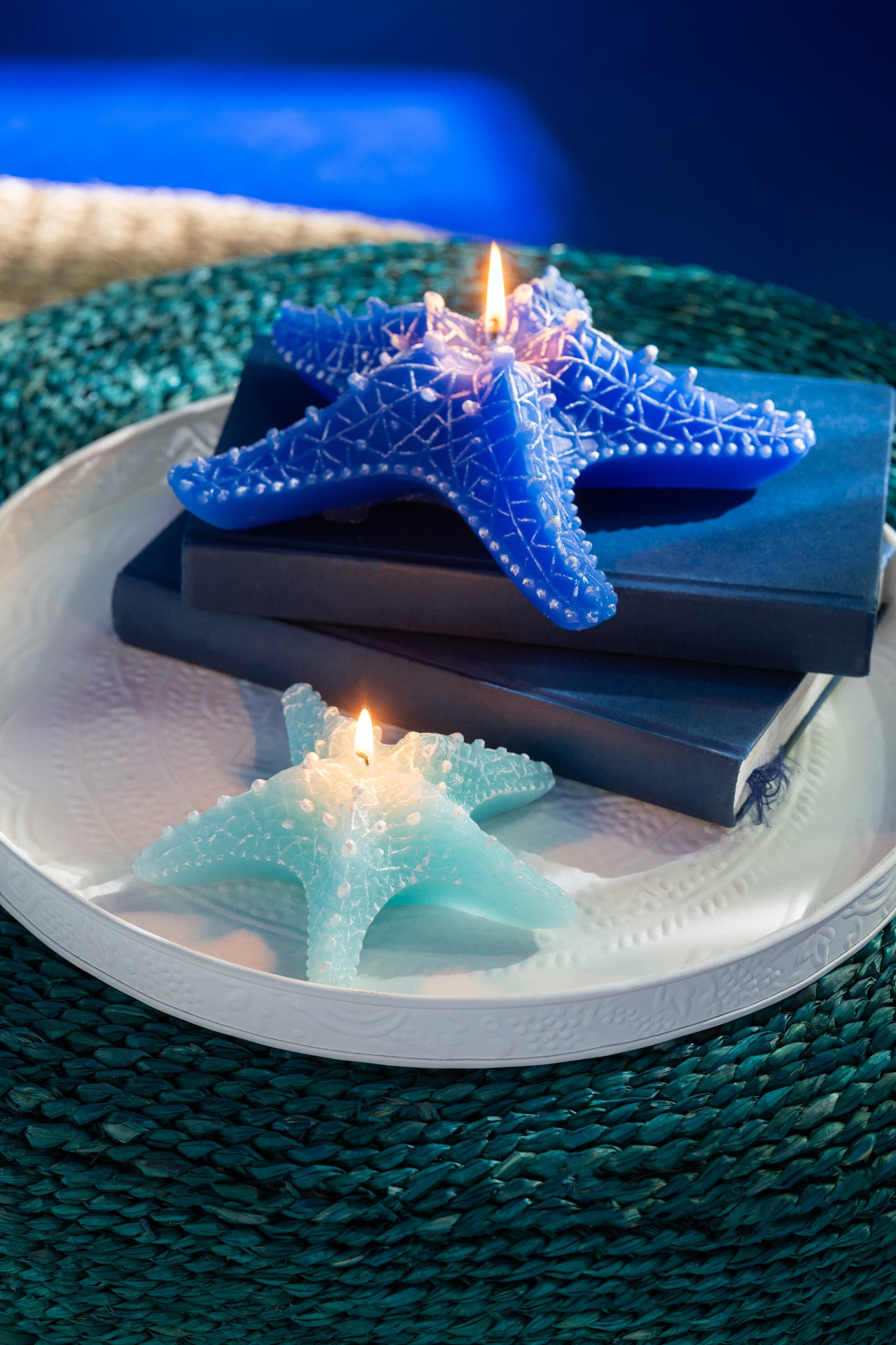 Candela a forma di stella marina piccola azzurra firmata Jolipa, perfetta come elemento decorativo e centrotavola per una casa in stile marino o costiero. Il complemento d'arredo presenta dettagli realistici in rilievo con sfumature bianche ed è fotografato su un fondo bianco isolato.
