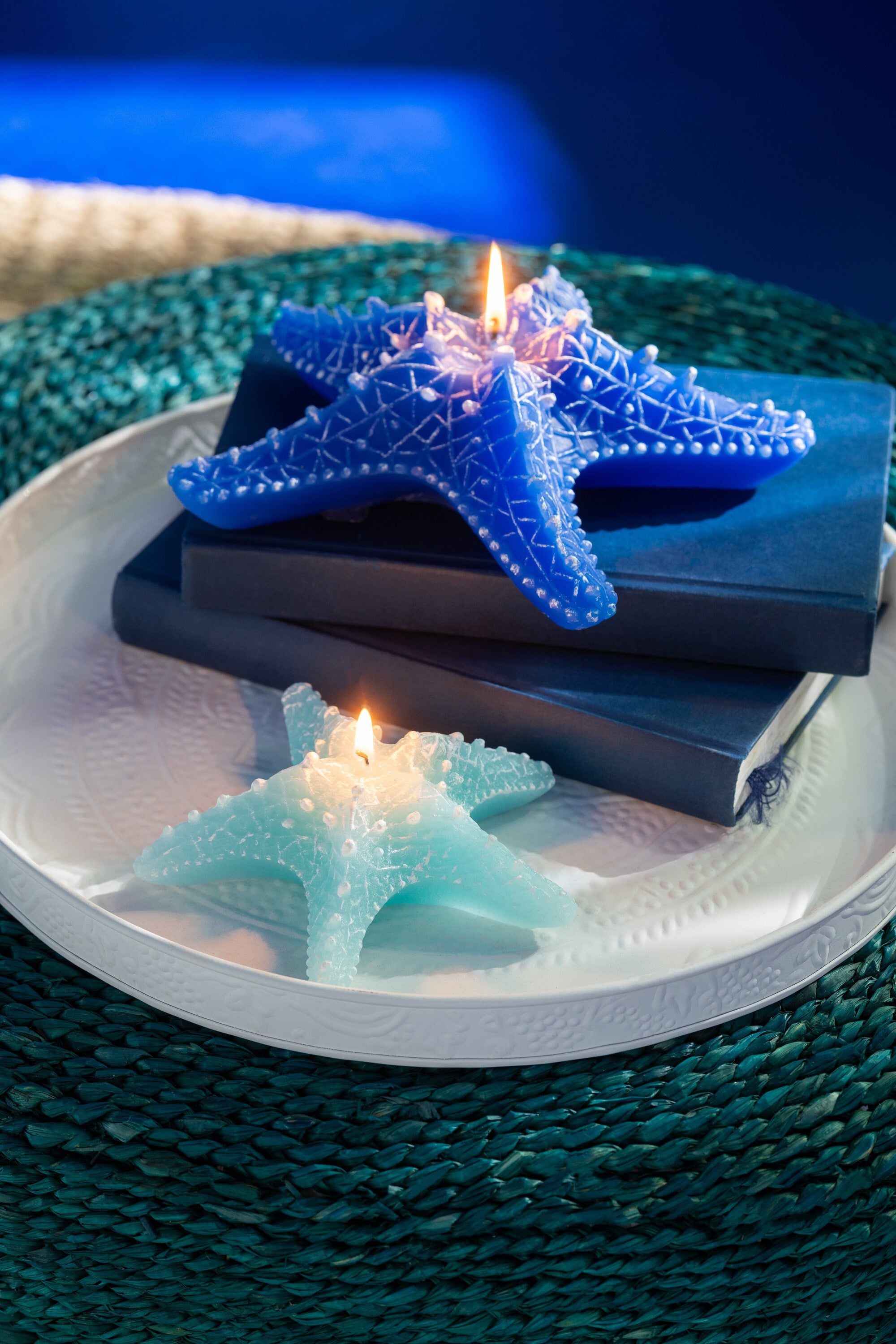 Candela a forma di stella marina piccola azzurra firmata Jolipa, perfetta come elemento decorativo e centrotavola per una casa in stile marino o costiero. Il complemento d'arredo presenta dettagli realistici in rilievo con sfumature bianche ed è fotografato su un fondo bianco isolato.