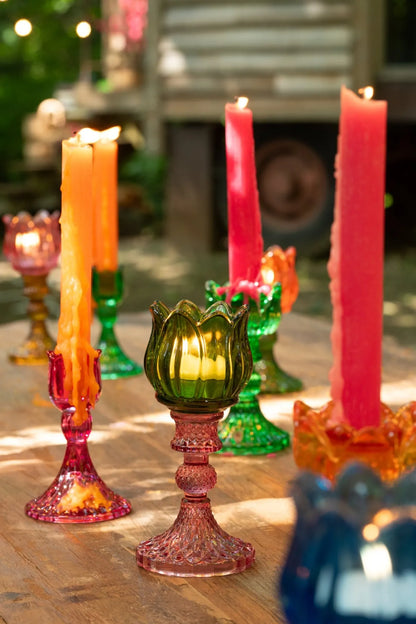 Candelabri alti a forma di tulipano in vetro mix colorato assortiti, caratterizzati da una sommità a bocciolo lavorata a costine e da uno stelo decorativo con base svasata impreziosita da una trama diamantata a rilievo. Disponibili in tre vivaci combinazioni di colore bicolore con calici blu, rosa e verde abbinati a basi arancioni, ambra e rosa sfumate, questi eleganti portacandele di design sono ideali per completare l'home decor con un tocco originale e sofisticato.