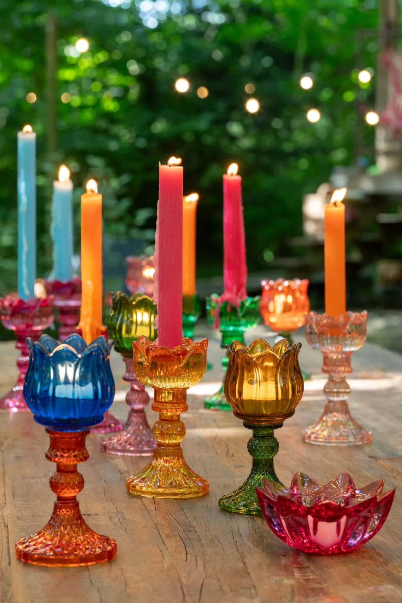 Candelabri alti a forma di tulipano in vetro mix colorato assortiti, caratterizzati da una sommità a bocciolo lavorata a costine e da uno stelo decorativo con base svasata impreziosita da una trama diamantata a rilievo. Disponibili in tre vivaci combinazioni di colore bicolore con calici blu, rosa e verde abbinati a basi arancioni, ambra e rosa sfumate, questi eleganti portacandele di design sono ideali per completare l'home decor con un tocco originale e sofisticato.