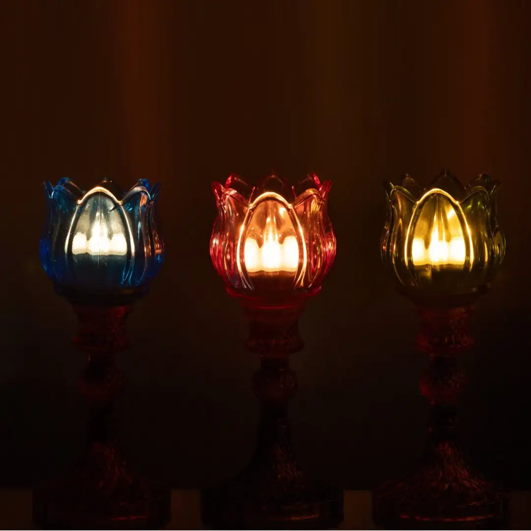 Candelabri alti a forma di tulipano in vetro mix colorato assortiti, caratterizzati da una sommità a bocciolo lavorata a costine e da uno stelo decorativo con base svasata impreziosita da una trama diamantata a rilievo. Disponibili in tre vivaci combinazioni di colore bicolore con calici blu, rosa e verde abbinati a basi arancioni, ambra e rosa sfumate, questi eleganti portacandele di design sono ideali per completare l'home decor con un tocco originale e sofisticato.
