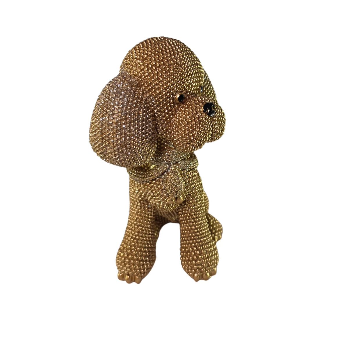 Statuina in resina raffigurante un cagnolino dorato seduto con lunghe orecchie pendenti e una sciarpa arrotolata al collo, interamente ricoperto di brillantini glitterati, con occhi e naso neri. Oggetto decorativo scintillante firmato Sud Import, ideale come soprammobile per bambini o idea regalo per gli amanti degli animali.