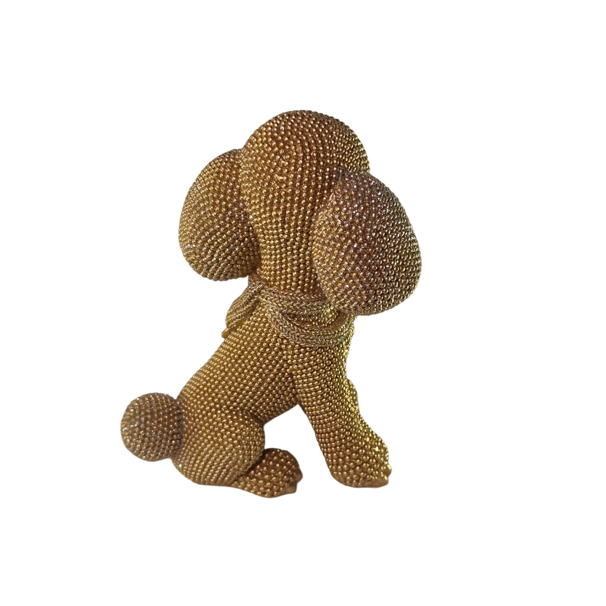 Statuina in resina raffigurante un cagnolino dorato seduto con lunghe orecchie pendenti e una sciarpa arrotolata al collo, interamente ricoperto di brillantini glitterati, con occhi e naso neri. Oggetto decorativo scintillante firmato Sud Import, ideale come soprammobile per bambini o idea regalo per gli amanti degli animali.