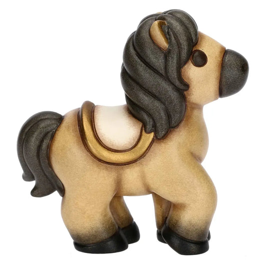 Statuina in ceramica del cavallo Isabella di piccole dimensioni firmata THUN, caratterizzata da un corpo nei toni caldi del beige con criniera, coda e zoccoli scuri sfumati. La figura da collezione presenta forme dolci e arrotondate tipiche del marchio, arricchita da una sella color panna con dettagli dorati sul dorso che la rende un'ottima idea regalo o un elemento decorativo per la casa.