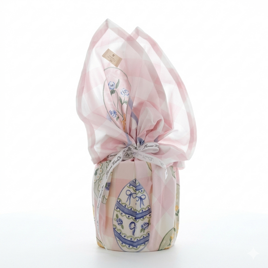 Foulard centrotavola della collezione "Pretty Easter" avvolto a forma di uovo di Pasqua e chiuso da un nastro bianco logato. Il tessuto presenta una delicata fantasia a scacchi bianchi e rosa confetto impreziosita da illustrazioni di uova pasquali decorate con roselline azzurre e fiocchi, ideale per arricchire la tavola primaverile in perfetto stile shabby chic.