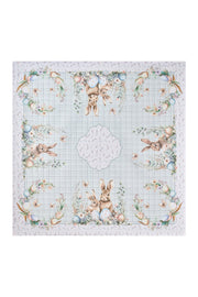 Centrotavola pasquale Nuvole di Stoffa in cotone celeste a quadretti vichy. Decorazione con illustrazioni di coniglietti, uova colorate e fiori delicati. Elegante tessile tavola per Pasqua 2026.