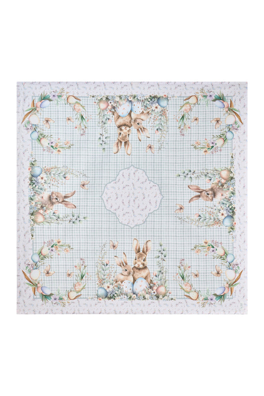 Centrotavola pasquale Nuvole di Stoffa in cotone celeste a quadretti vichy. Decorazione con illustrazioni di coniglietti, uova colorate e fiori delicati. Elegante tessile tavola per Pasqua 2026.
