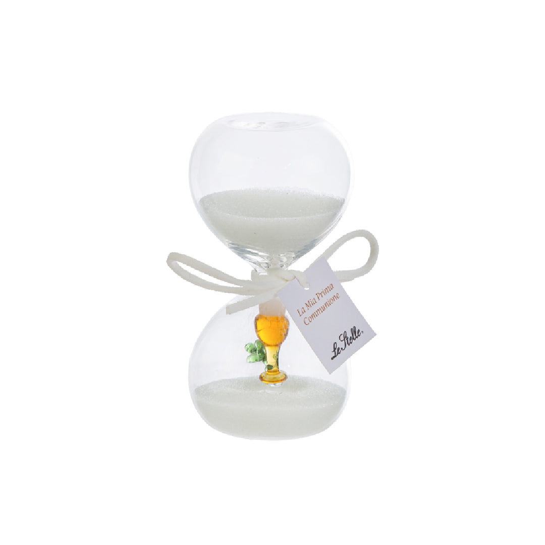 Clessidra in vetro trasparente riempita di sabbia bianca, con un calice dorato e un rametto verde all'interno del bulbo inferiore e fiocco bianco con etichetta "La mia prima Comunione". Bomboniera decorativa presentata con la sua confezione bianca del marchio Le Stelle, ideale come ricordo per la Prima Comunione.