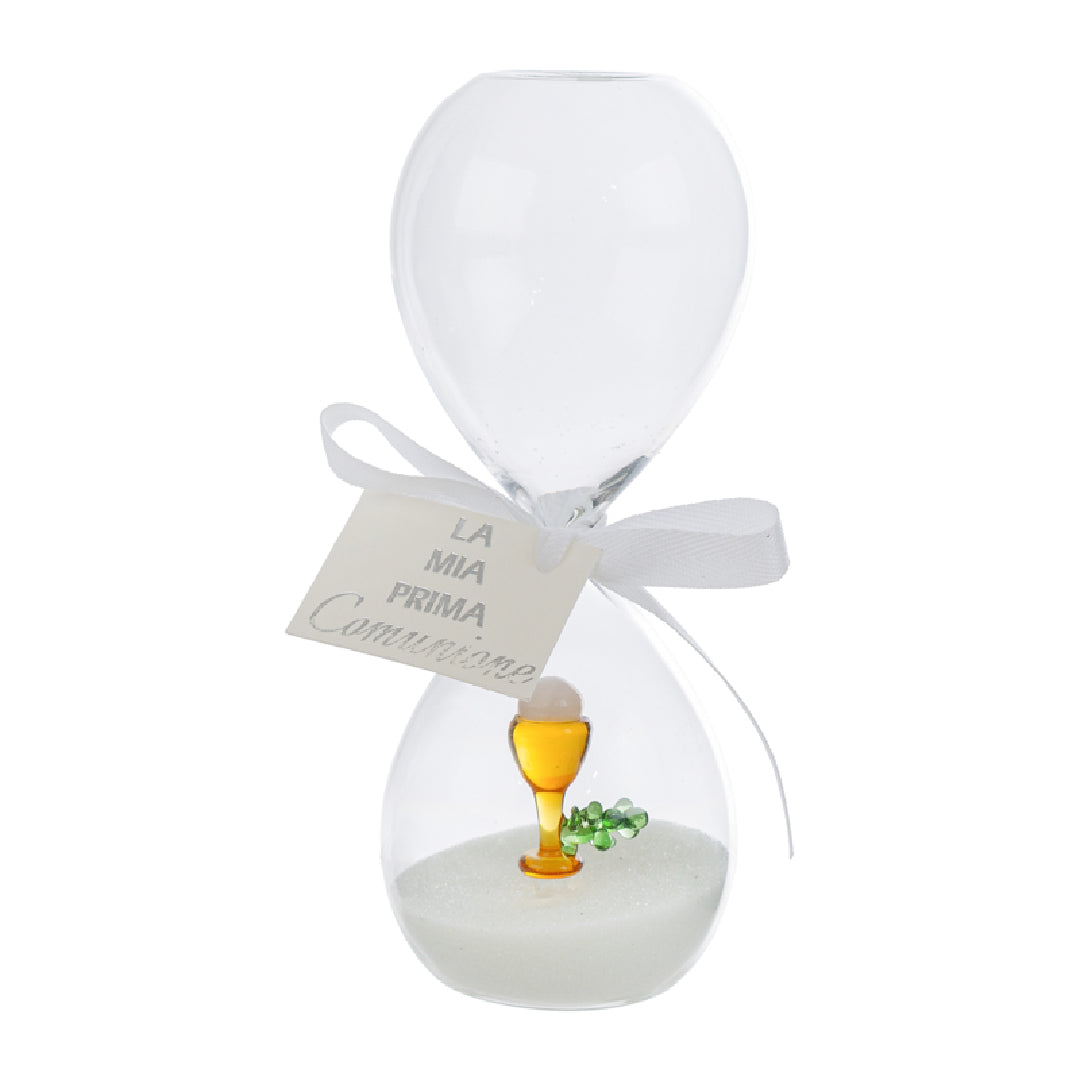 Clessidra in vetro trasparente riempita di sabbia bianca, con un calice dorato e un rametto verde all'interno del bulbo inferiore e fiocco bianco con etichetta "La mia prima Comunione". Bomboniera decorativa presentata con la sua confezione bianca del marchio Le Stelle, ideale come ricordo per la Prima Comunione.