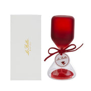 Clessidra in vetro satinato rosso a forma di clava, con base conica trasparente riempita di sabbia rossa e cordoncino con etichetta tonda "Le Stelle" decorata da un cappello di laurea. Oggetto decorativo elegante presentato con la sua confezione bianca del marchio, ideale come bomboniera per lauree o idea regalo raffinata.