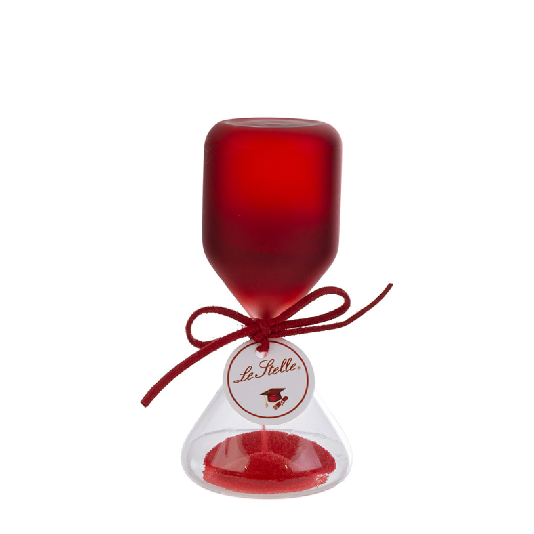 Clessidra in vetro satinato rosso a forma di clava, con base conica trasparente riempita di sabbia rossa e cordoncino con etichetta tonda "Le Stelle" decorata da un cappello di laurea. Oggetto decorativo elegante presentato con la sua confezione bianca del marchio, ideale come bomboniera per lauree o idea regalo raffinata.