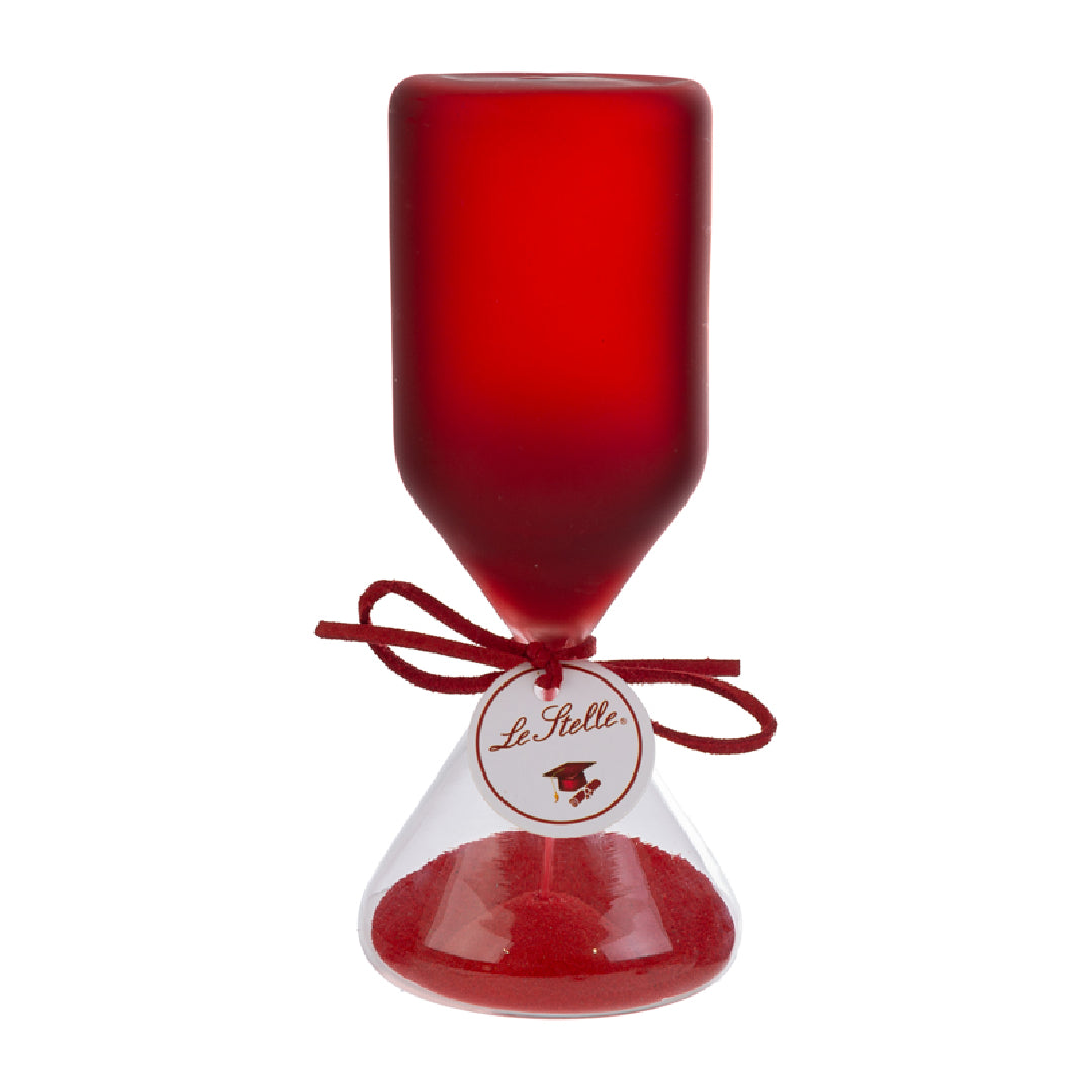Clessidra in vetro satinato rosso a forma di clava, con base conica trasparente riempita di sabbia rossa e cordoncino con etichetta tonda "Le Stelle" decorata da un cappello di laurea. Oggetto decorativo elegante presentato con la sua confezione bianca del marchio, ideale come bomboniera per lauree o idea regalo raffinata.