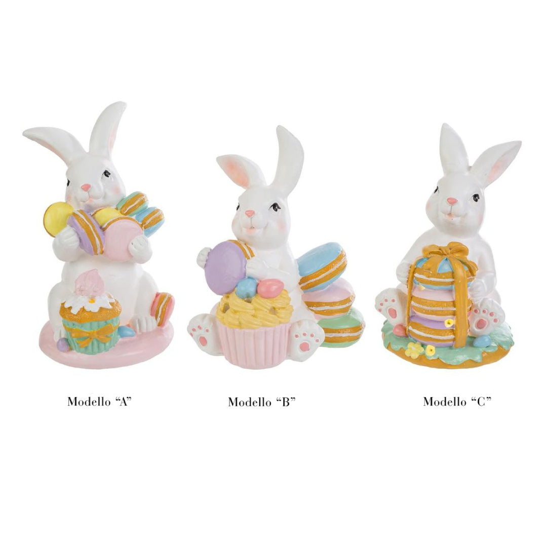 Tris di statuine pasquali assortite del marchio Le Stelle (codice 12244) raffiguranti coniglietti bianchi con dolci e pasticcini. Il Modello A tiene dei macaron e ha un cupcake alla base; il Modello B è seduto accanto a una pila di macaron e un grande pasticcino; il Modello C tiene una torre di macaron legata con un fiocco dorato. Decorazioni in resina dai colori pastello.