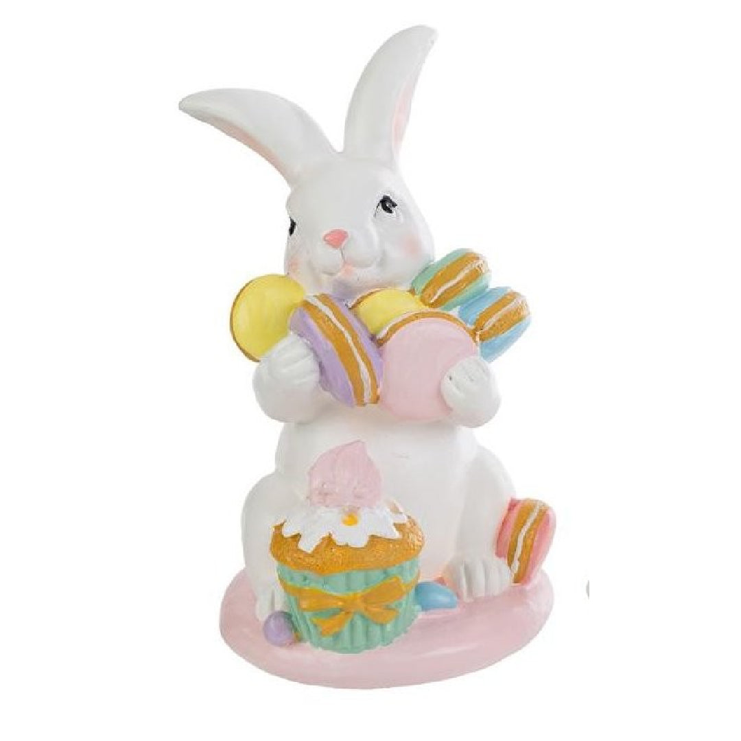 Tris di statuine pasquali assortite del marchio Le Stelle (codice 12244) raffiguranti coniglietti bianchi con dolci e pasticcini. Il Modello A tiene dei macaron e ha un cupcake alla base; il Modello B è seduto accanto a una pila di macaron e un grande pasticcino; il Modello C tiene una torre di macaron legata con un fiocco dorato. Decorazioni in resina dai colori pastello.