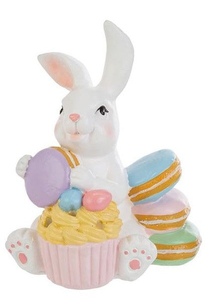 Tris di statuine pasquali assortite del marchio Le Stelle (codice 12244) raffiguranti coniglietti bianchi con dolci e pasticcini. Il Modello A tiene dei macaron e ha un cupcake alla base; il Modello B è seduto accanto a una pila di macaron e un grande pasticcino; il Modello C tiene una torre di macaron legata con un fiocco dorato. Decorazioni in resina dai colori pastello.