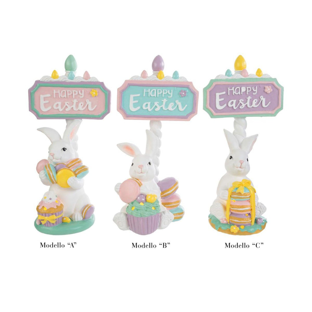 Tris di statuine pasquali assortite del marchio Le Stelle (codice 12245) raffiguranti coniglietti bianchi con dolci e pasticcini, davanti delle targhe "Happy Easter". Il Modello A tiene dei macaron e ha un cupcake alla base; il Modello B è seduto accanto a una pila di macaron e un grande pasticcino; il Modello C tiene una torre di macaron legata con un fiocco dorato. Decorazioni in resina dai colori pastello.
