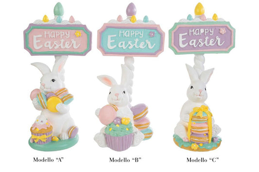 Tris di statuine pasquali assortite del marchio Le Stelle (codice 12245) raffiguranti coniglietti bianchi con dolci e pasticcini, davanti delle targhe "Happy Easter". Il Modello A tiene dei macaron e ha un cupcake alla base; il Modello B è seduto accanto a una pila di macaron e un grande pasticcino; il Modello C tiene una torre di macaron legata con un fiocco dorato. Decorazioni in resina dai colori pastello.