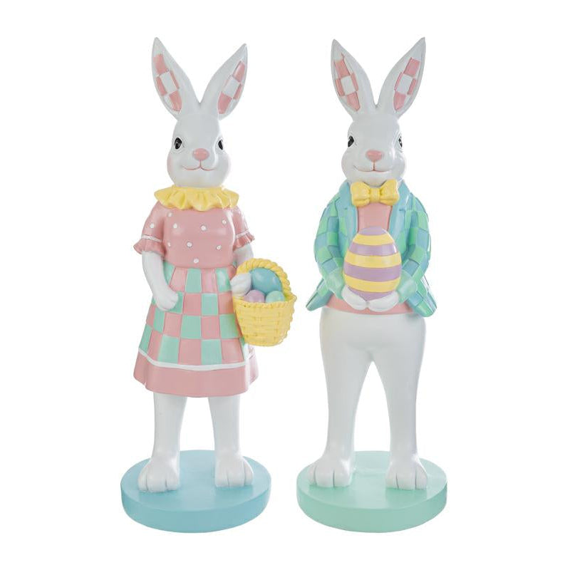 Coppia di statuine decorative a forma di conigli bianchi in piedi su basi circolari color pastello. La coniglietta indossa un abito rosa a pois con gonna a scacchi verdi e tiene un cestino di uova; il coniglio indossa una giacca a scacchi azzurri e verdi con papillon giallo e regge un uovo decorato. Design in stile MacKenzie-Childs per il marchio Le Stelle.