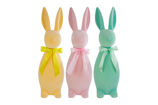 Tris di coniglietti pasquali decorativi del marchio Le Stelle (codice 12224) con finitura floccata effetto velluto. Il set comprende tre varianti di colore pastello: giallo ocra, rosa cipria e verde acqua, ognuna ornata da un fiocco in raso coordinato. Statuine dal design stilizzato e moderno per l'arredamento di Pasqua.